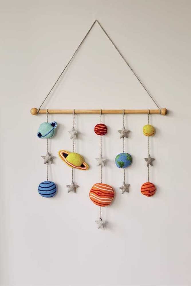 a mobile with planets and stars hanging from it's sides on a wall next to a white wall