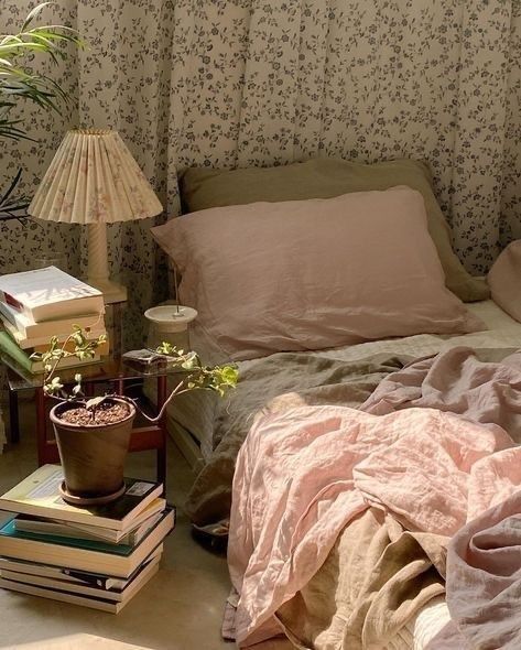 a bed with pillows and blankets on top of it next to a table with books