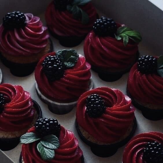 a box filled with red velvet cupcakes topped with blackberries