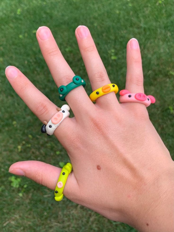 a person's hand with five different colored rings on it, all in the shape of animals