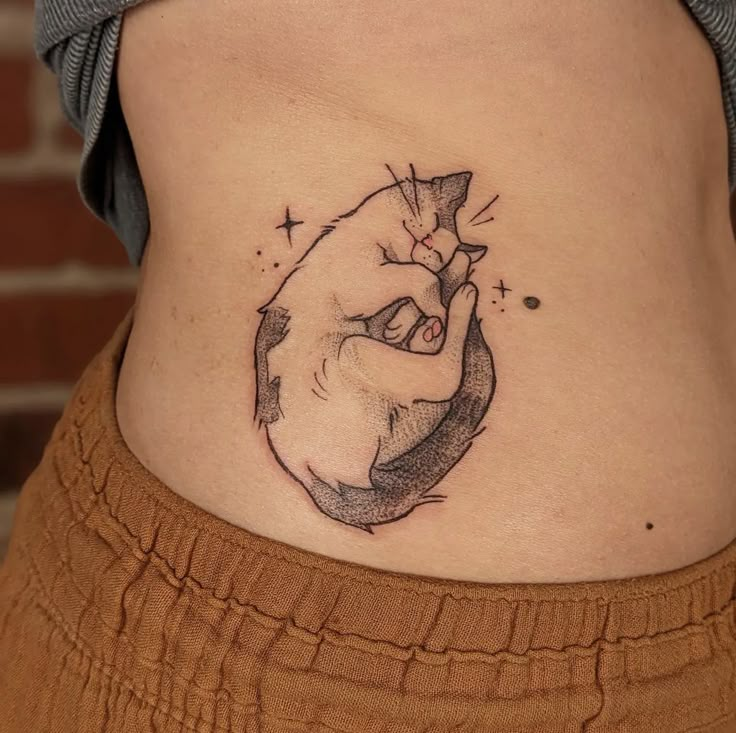 a woman's stomach with a small tattoo on the side of her belly, showing an image of a hand holding a diamond