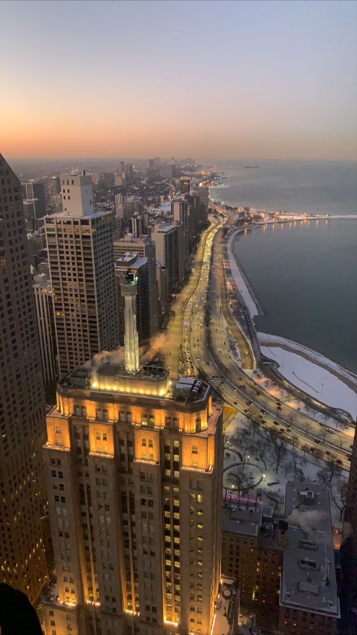 an aerial view of the chicago skyline at night with lights on and water in the background