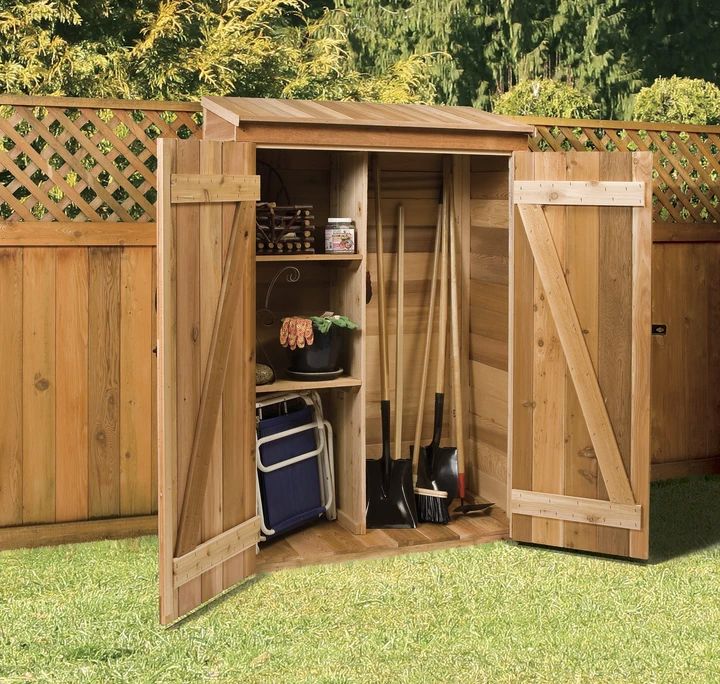 a wooden shed with its doors open and gardening tools in the storage compartment inside it