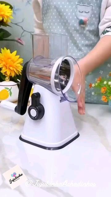 a person is using an electric juicer on a counter top with flowers in the background