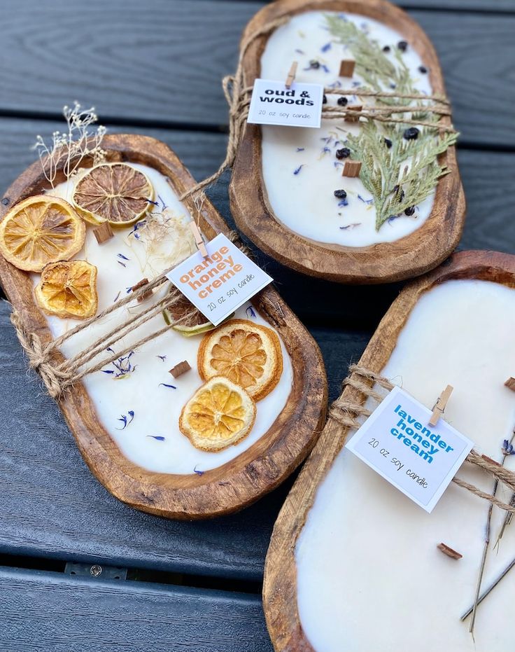 three wooden trays with dried orange slices and herbs on them sitting on a table