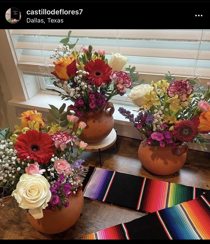 three vases filled with different types of flowers on a table next to a window