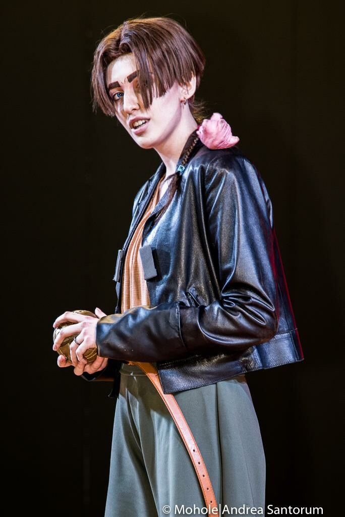 a woman in black leather jacket holding a pink flower