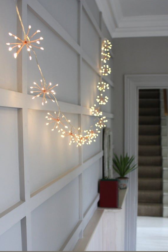 a white wall with lights hanging from it's sides and a plant in the middle