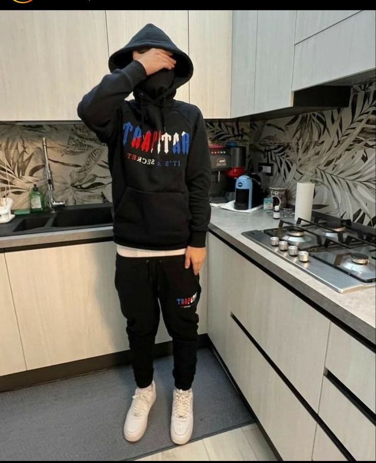 a person standing in a kitchen wearing a black hoodie and sweatpants with the words atlanta on it