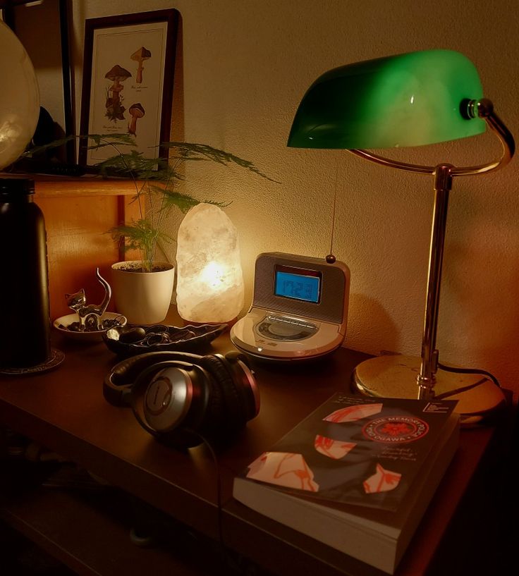 a green lamp sitting on top of a table next to a book and headphones