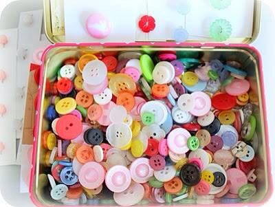 a pink tin filled with lots of different colored buttons