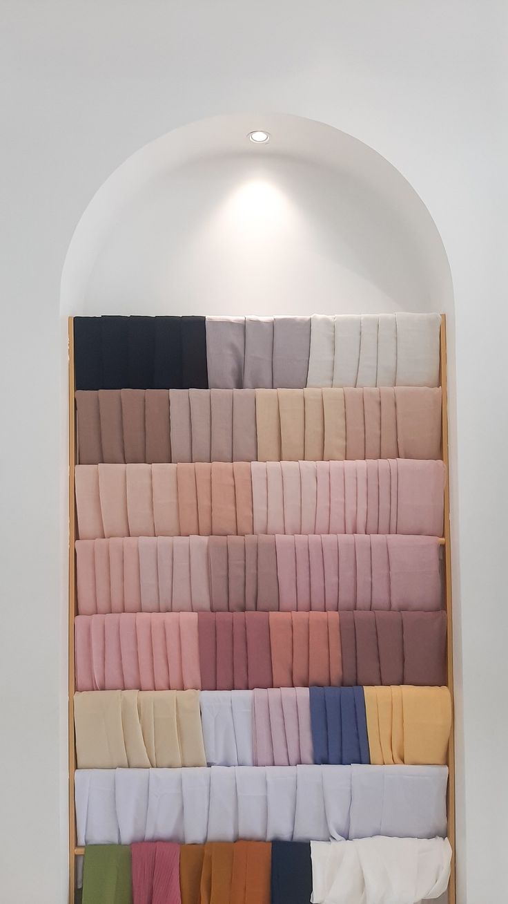 an assortment of folded and unbuttoned sheets on display in a white walled room