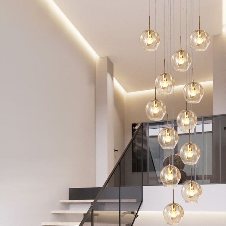 a modern chandelier hanging from the ceiling in a room with stairs and windows