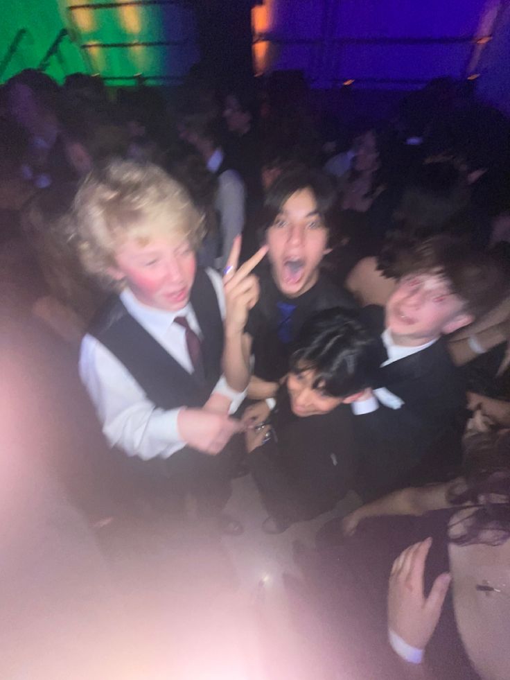 two boys in vests and ties are dancing at a party with other people behind them