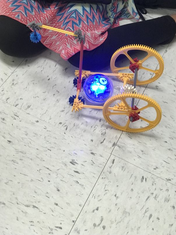 a person sitting on the ground with a toy bike in front of them and an electronic light up bicycle next to it