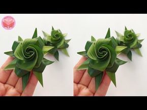 two hands holding green paper flowers on top of each other with spirals in the middle