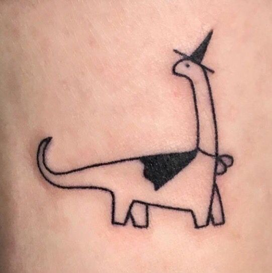 a small black and white dinosaur tattoo on the back of a woman's thigh