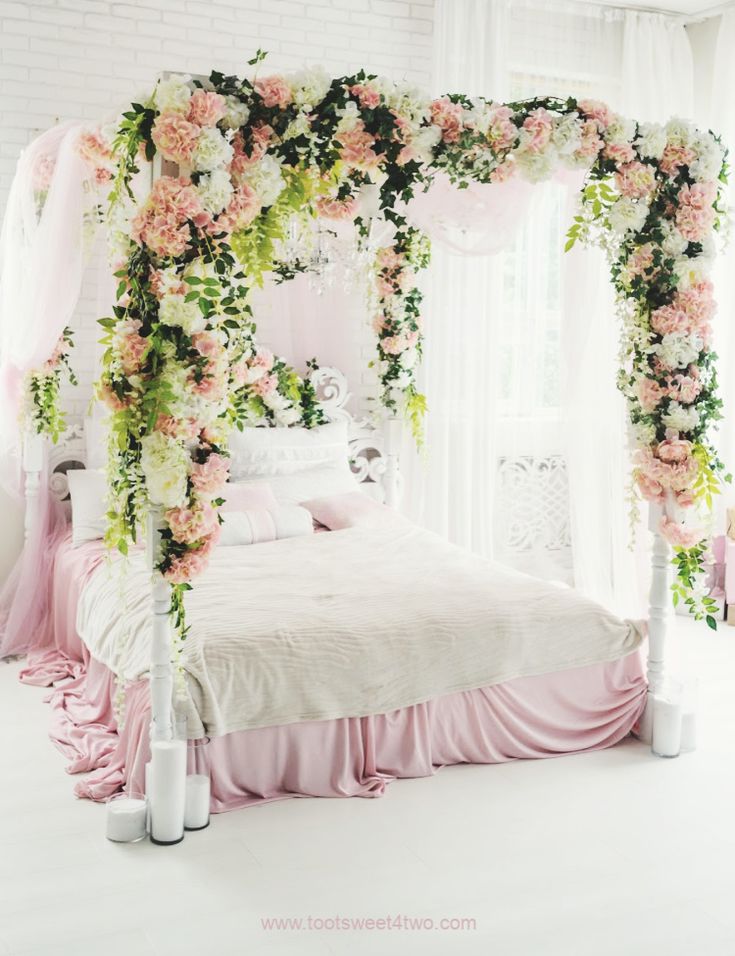 a bedroom decorated in pink and white with flowers on the headboard, canopy bed