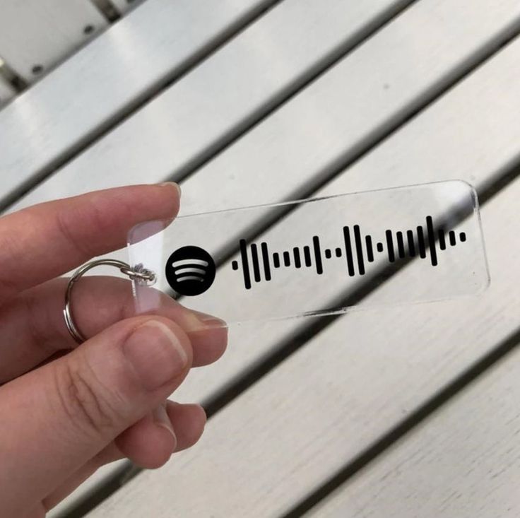 a person is holding a key chain with sound waves on it and the word music spelled in black