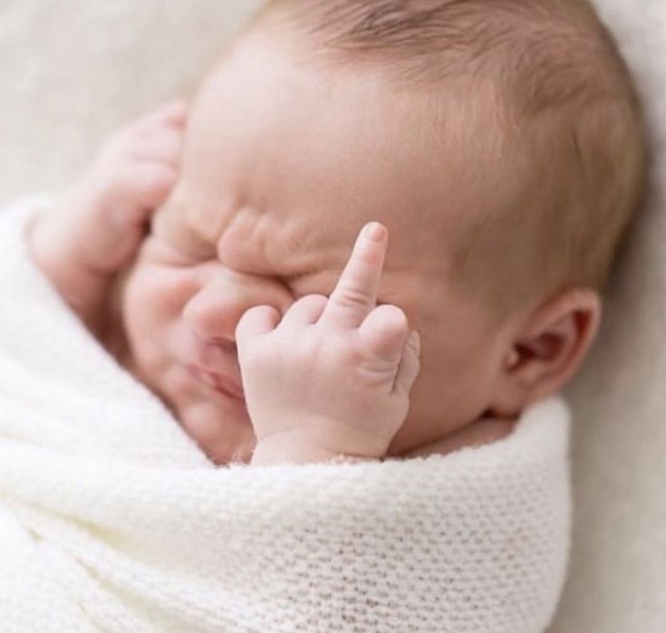 a newborn baby wrapped in a blanket is holding his hand up