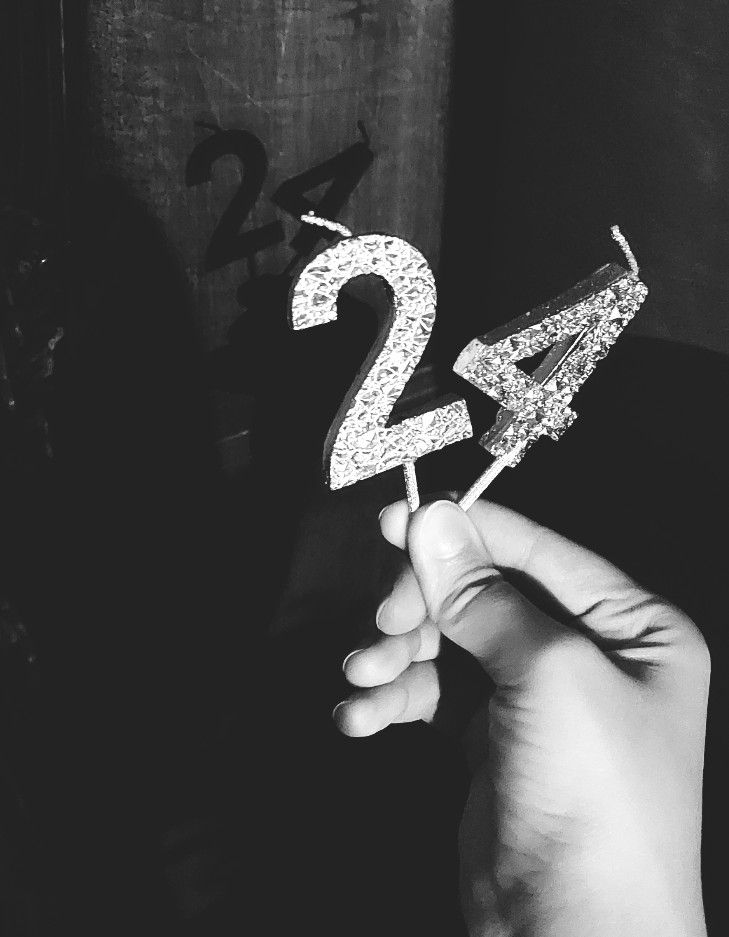 a hand holding a cake topper with the number twenty two in it's middle