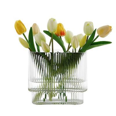 a vase filled with yellow and white tulips sitting on top of a table