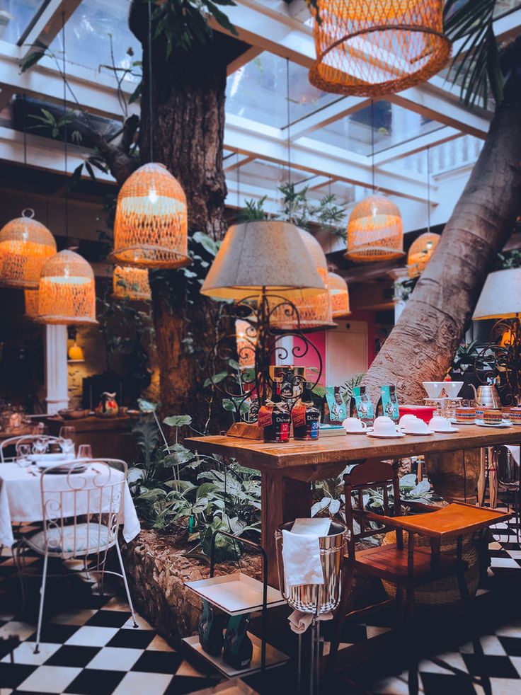 a restaurant with tables, chairs and lamps hanging from the ceiling in front of palm trees