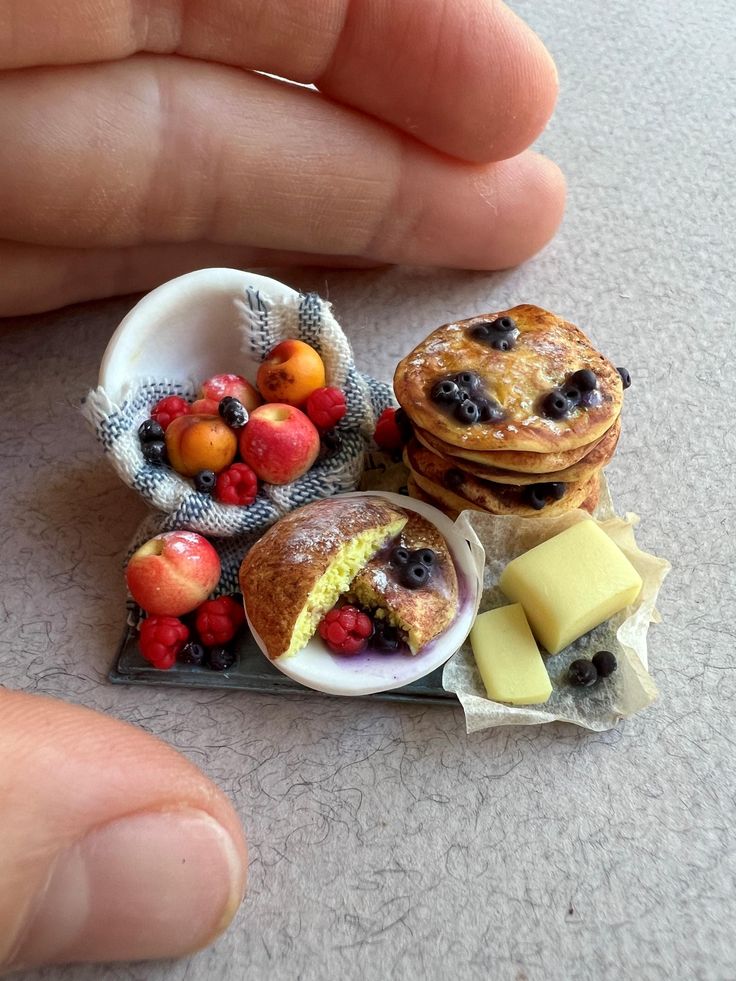 there is a miniature pancake with fruit on it and cheese in the bowl next to it