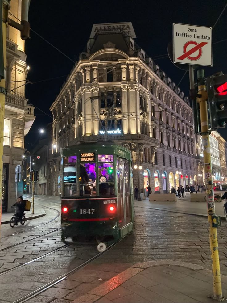 a trolley is going down the street in front of an old building at night time