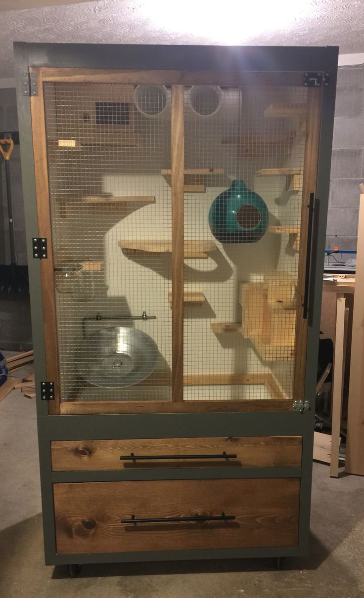 a large bird cage sitting inside of a wooden cabinet