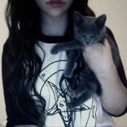 a woman holding two kittens in her arms while wearing a t - shirt with the image of jesus on it