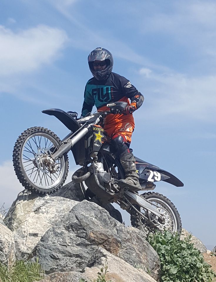 a man on a dirt bike jumping over rocks in the air with his helmet on