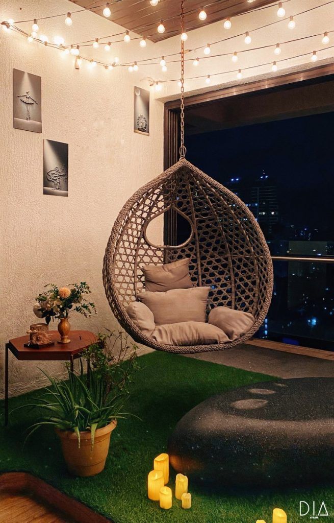 a hanging chair in the corner of a room with lights strung from the ceiling and potted plants