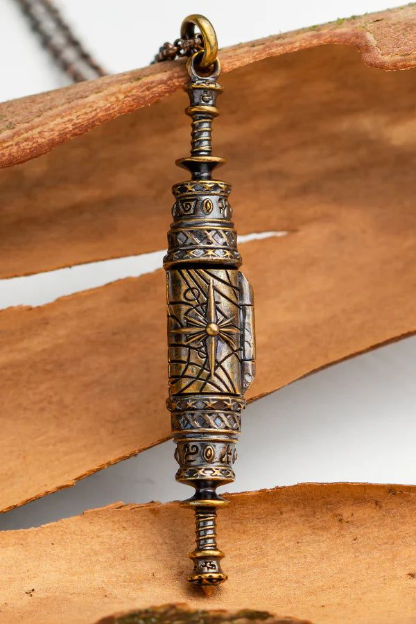 an ornate metal object sitting on top of a piece of wood next to a chain