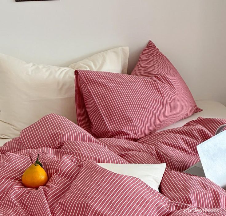 a red and white striped comforter on a bed with a pear in the corner