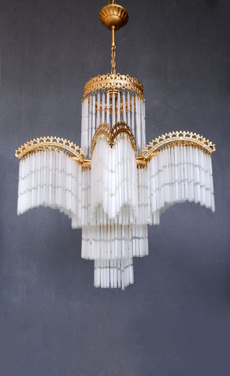 a chandelier hanging from the ceiling with white and gold trimmings on it