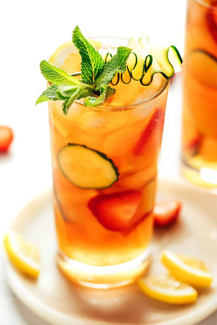 two glasses filled with drinks sitting on top of a white plate