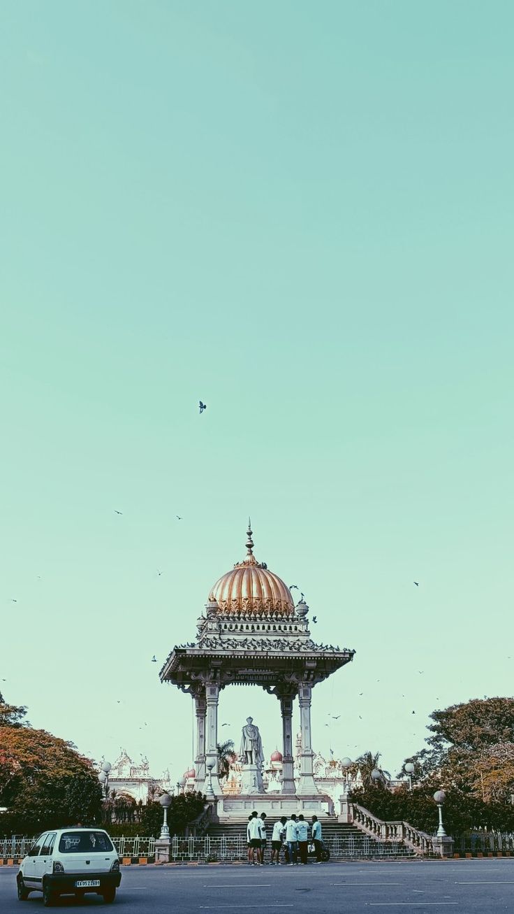 a car driving down a street next to a tall building with a dome on top