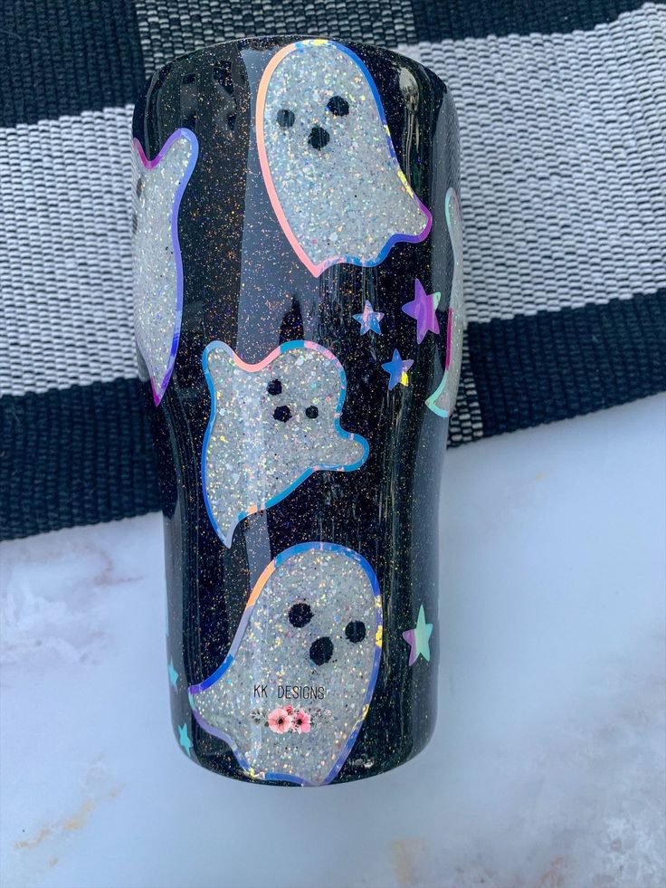 a black tumbler with ghost and stars on it