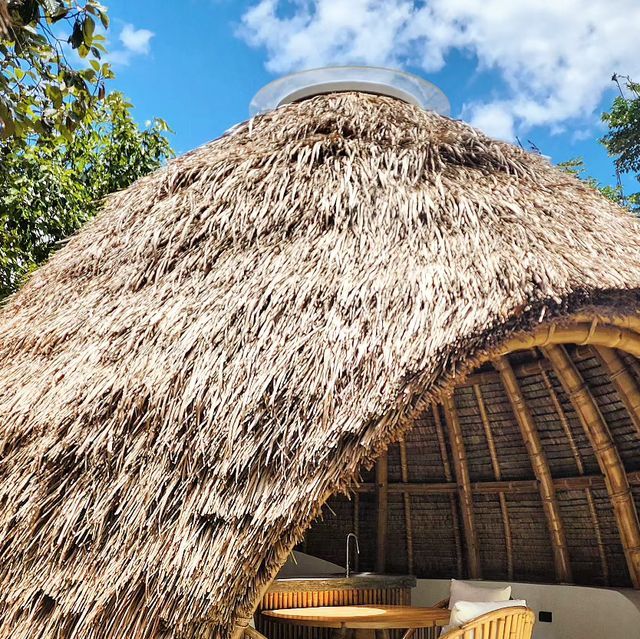 a thatched roof with wicker chairs around it