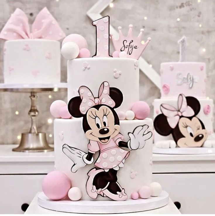 there is a birthday cake decorated with minnie mouses and pink decorations on the table