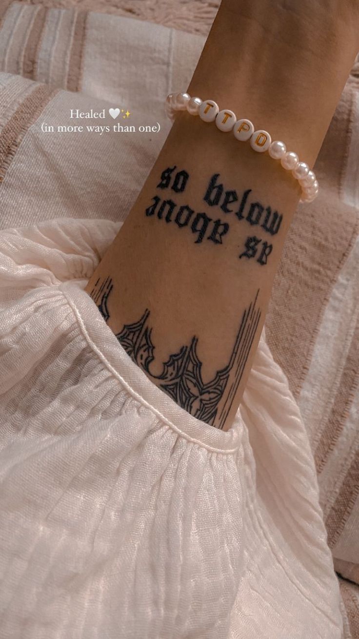 a woman with a tattoo on her wrist that says, go below the bridge at night