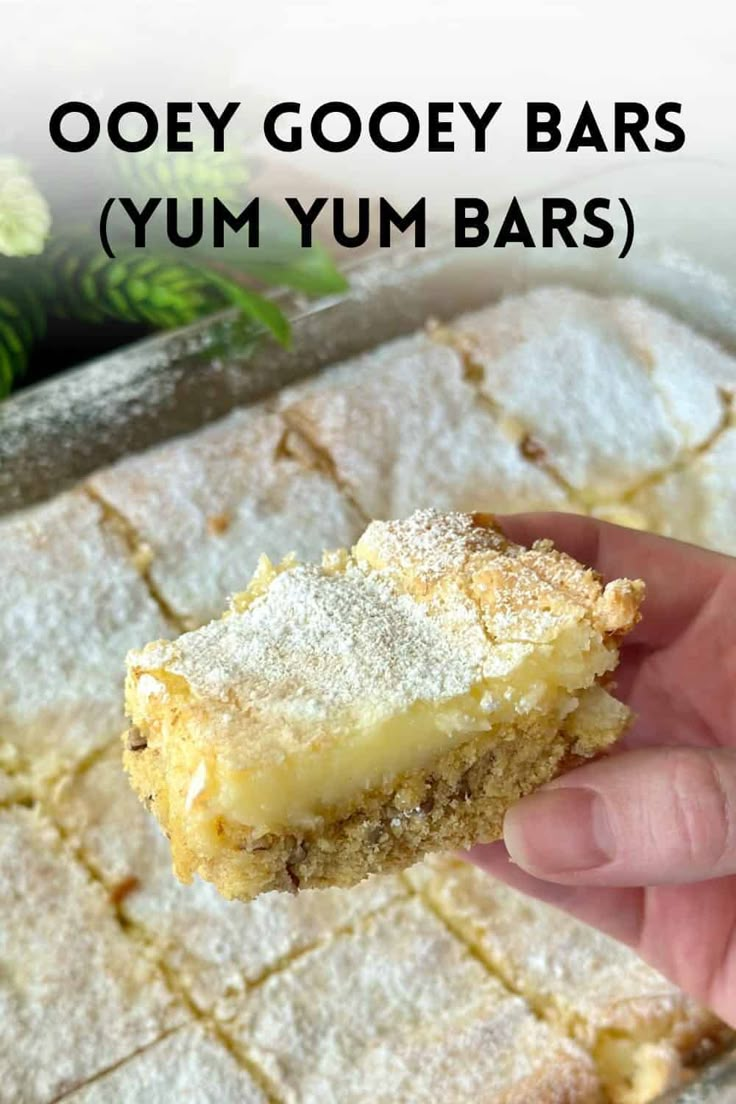 a hand holding up a piece of gooey gooey bars yum yum bars