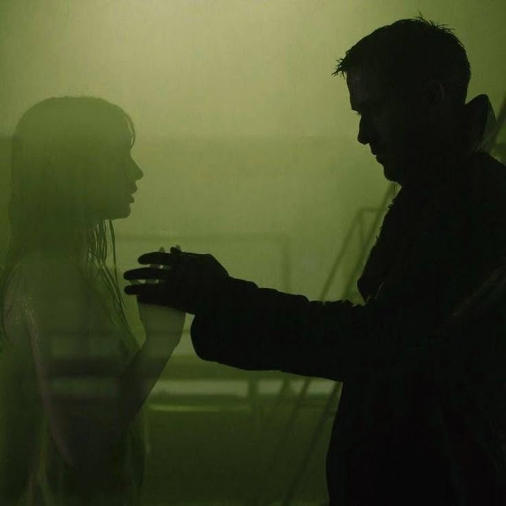 a man and woman standing next to each other in front of a green wall with fog