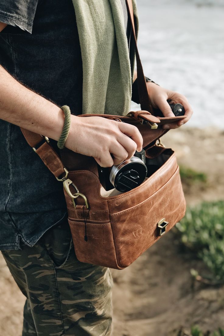 a man holding a camera in his brown bag