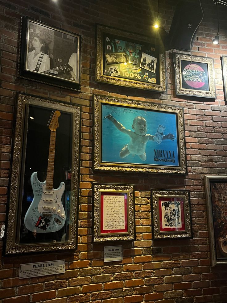 a brick wall with various framed pictures and guitars hanging on it's sides, along with guitar memorabilia