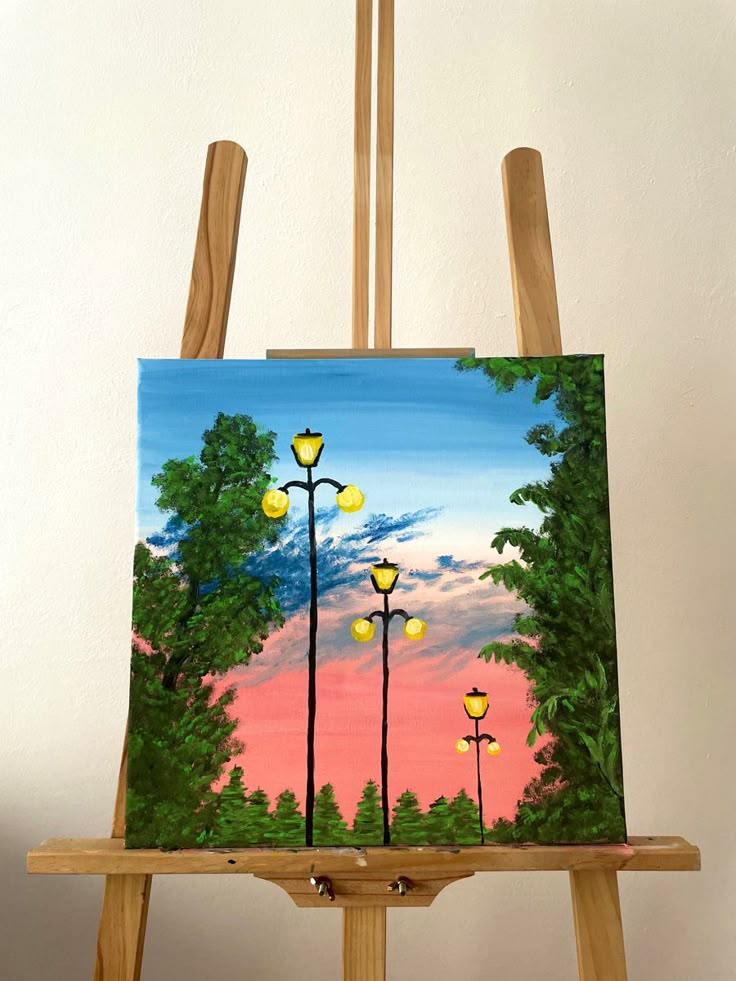 an easel with a painting on it holding a lamp post and street lights in the background