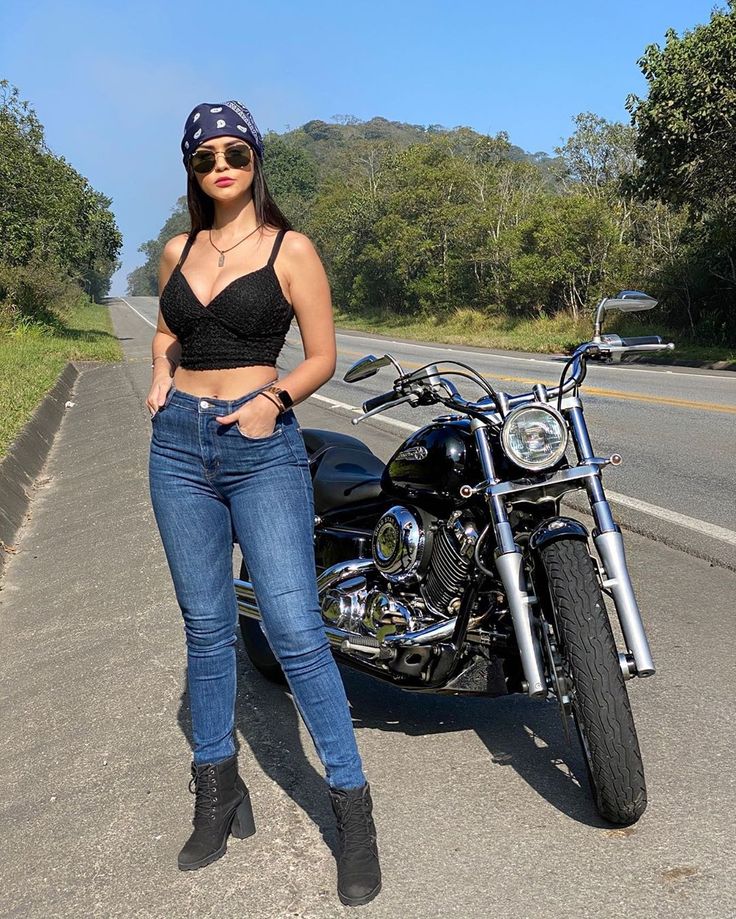 a woman standing next to a motorcycle on the road