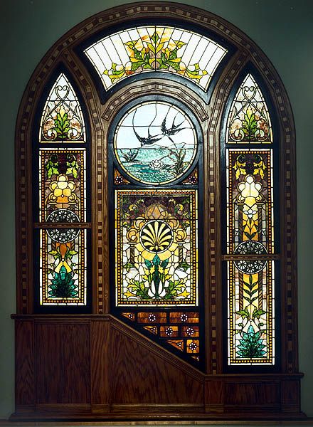 an ornate stained glass window in the corner of a room with stairs leading up to it