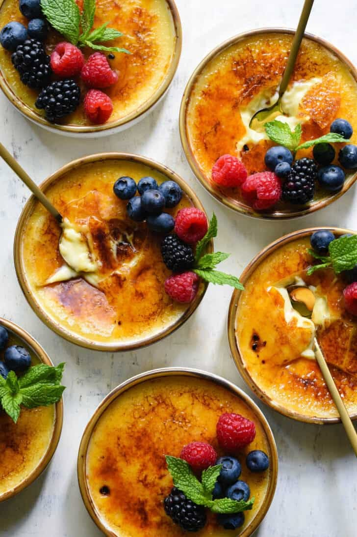 four bowls filled with dessert and topped with berries